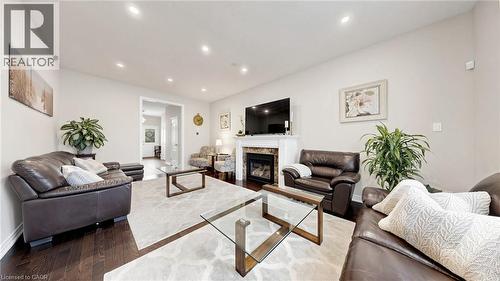 Recessed lighting, wood-finish flooring, and a fireplace with a mantel and stone surround - 173 Raymond Road, Ancaster, ON - Indoor Photo Showing Living Room With Fireplace