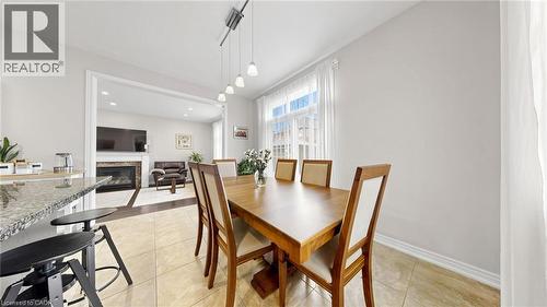 Dining area with tile flooring and track lighting, featuring a window with natural light and an open doorway to a living space with a fireplace - 173 Raymond Road, Ancaster, ON - Indoor Photo Showing Dining Room