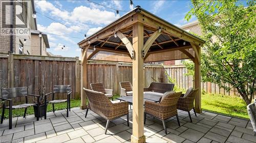 Stone paver patio with a wood gazebo, string lighting, and a wood fence enclosure - 173 Raymond Road, Ancaster, ON - Outdoor With Deck Patio Veranda