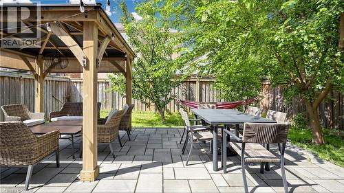 Expansive paver patio featuring a wooden gazebo with string lights, mature trees, and a wooden privacy fence - 173 Raymond Road, Ancaster, ON - Outdoor With Deck Patio Veranda