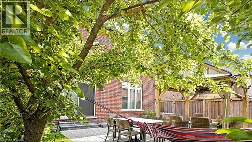 Brick exterior, paved patio, wood pergola, privacy fencing, and mature trees - 173 Raymond Road, Ancaster, ON - Outdoor With Deck Patio Veranda