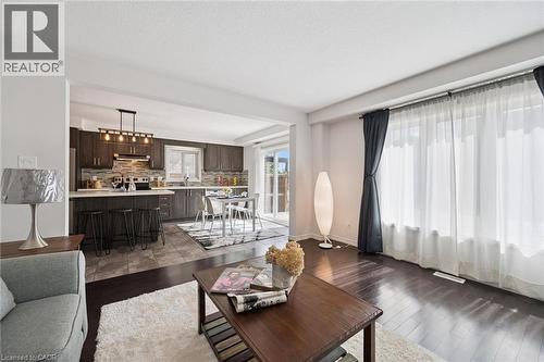 Open concept design with dark wood-finish flooring, a kitchen featuring dark wood cabinetry, a light-colored countertop, and a tile backsplash, and a dining area with direct access to an outdoor space - 360 Freure Drive, Cambridge, ON - Indoor Photo Showing Living Room