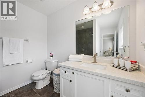 Bathroom featuring a single vanity with an integrated sink, light-colored countertop, white cabinetry, dark tile flooring, and a glass-enclosed shower - 360 Freure Drive, Cambridge, ON - Indoor Photo Showing Bathroom