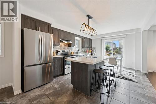 Kitchen featuring stainless steel appliances, wood-finish cabinetry, a central island with a light-toned countertop, and tile flooring - 360 Freure Drive, Cambridge, ON - Indoor Photo Showing Kitchen With Upgraded Kitchen
