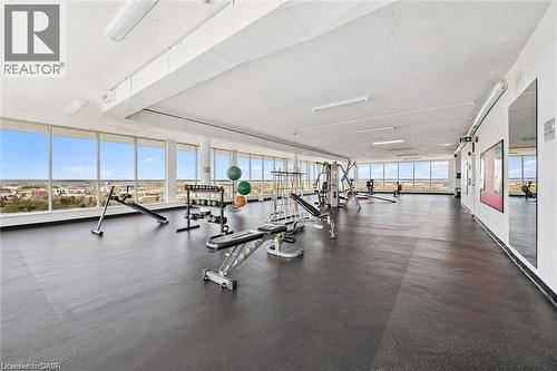 Spacious fitness area featuring floor-to-ceiling windows, soft rubber flooring, and integrated wall mirrors - 375 King Street N Unit# 708, Waterloo, ON - Indoor Photo Showing Gym Room