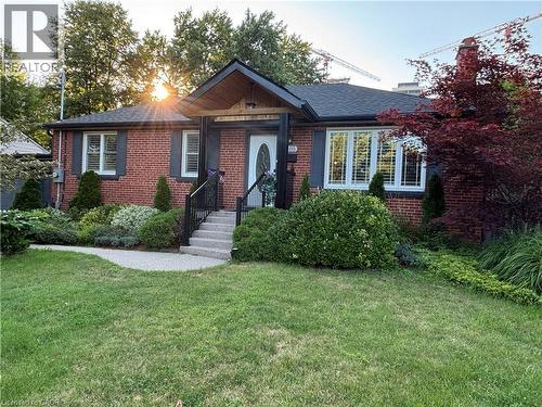 Brick exterior with dark shutters, front entry with stone steps, established landscaping, and a manicured lawn - 2105 Maplewood Drive, Burlington, ON - Outdoor