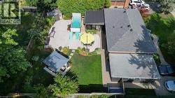 Expansive backyard featuring a concrete patio, a built-in swimming pool, a dedicated lawn area, a gazebo, and mature landscaping - 