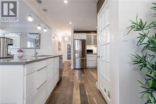Kitchen featuring a large island with an undermount sink, pendant lighting, recessed lighting, wood-finish flooring, and stainless steel appliances - 2105 Maplewood Drive, Burlington, ON - Indoor Photo Showing Kitchen With Stainless Steel Kitchen With Upgraded Kitchen