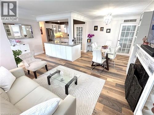 Open-concept living space featuring wood-finish flooring, a kitchen island with stone countertop, and an ornamental fireplace surround - 2105 Maplewood Drive, Burlington, ON - Indoor Photo Showing Living Room