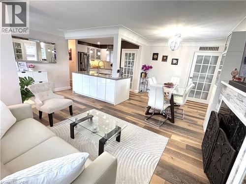 Wood-finish flooring throughout, kitchen island with seating, built-in fireplace with stone-look surround, and French pane doors - 2105 Maplewood Drive, Burlington, ON - Indoor Photo Showing Living Room