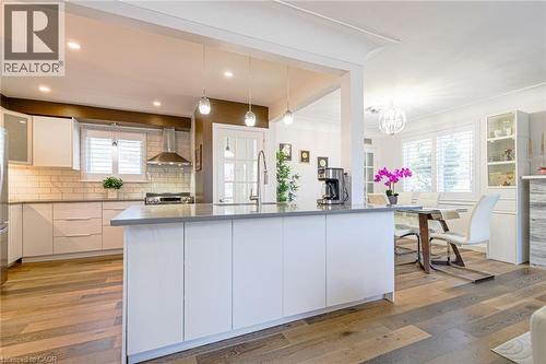 Kitchen featuring an expansive island with a solid surface countertop, wood-finish flooring, white cabinetry, subway tile backsplash, and stainless steel appliances - 2105 Maplewood Drive, Burlington, ON - Indoor Photo Showing Kitchen With Upgraded Kitchen