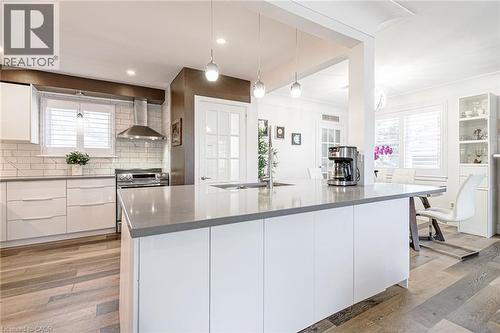 Expansive kitchen island with a neutral countertop, stainless steel appliances, wood-finish flooring, white cabinetry, and a subway tile backsplash - 2105 Maplewood Drive, Burlington, ON - Indoor Photo Showing Kitchen With Upgraded Kitchen