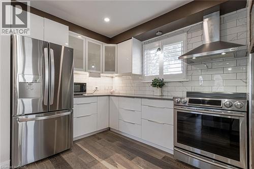 Sleek kitchen featuring stainless steel appliances, white flat-panel cabinetry, dark countertops, and wood-finish flooring - 2105 Maplewood Drive, Burlington, ON - Indoor Photo Showing Kitchen With Stainless Steel Kitchen