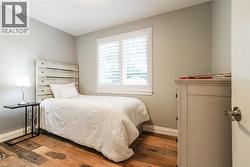 Wood-finish flooring, white window shutters, and a neutral wall color - 