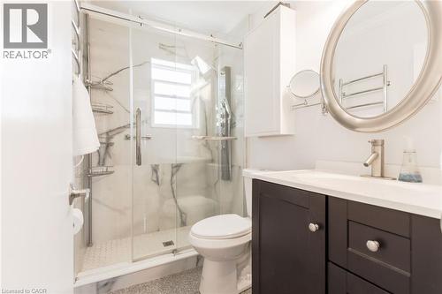 Glass-enclosed shower with white marble-style wall panels, hexagonal tile flooring, and a window - 2105 Maplewood Drive, Burlington, ON - Indoor Photo Showing Bathroom