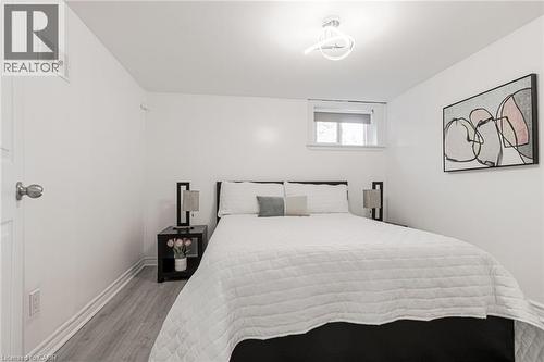 Clean white walls and ceiling, wood-finish flooring, a contemporary ceiling light fixture, and a window with a roller blind - 2105 Maplewood Drive, Burlington, ON - Indoor Photo Showing Bedroom