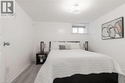 Clean white walls and ceiling, wood-finish flooring, a contemporary ceiling light fixture, and a window with a roller blind - 