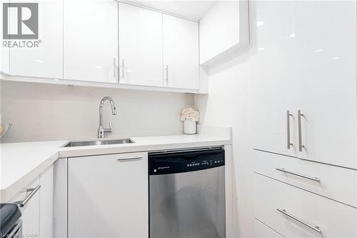 White high-gloss cabinetry, stainless steel sink with gooseneck faucet, integrated dishwasher, and white countertops with matching backsplash - 2105 Maplewood Drive, Burlington, ON - Indoor Photo Showing Kitchen With Double Sink