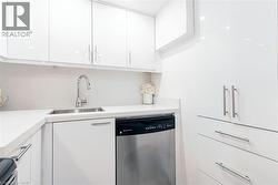 White high-gloss cabinetry, stainless steel sink with gooseneck faucet, integrated dishwasher, and white countertops with matching backsplash - 
