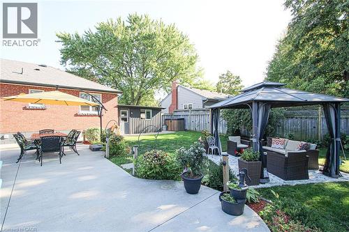 Expansive backyard featuring a concrete patio, lush green lawn, and mature trees - 2105 Maplewood Drive, Burlington, ON - Outdoor
