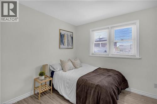 Neutral wall paint with white trim, wood-finish flooring, and a double window with blinds - 450 Highland Road E, Kitchener, ON - Indoor Photo Showing Bedroom
