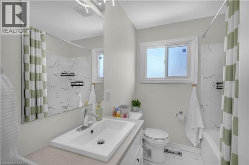 Contemporary bathroom featuring a single vanity with an integrated sink, a white toilet, and a bathtub with a shower - 450 Highland Road E, Kitchener, ON - Indoor Photo Showing Bathroom