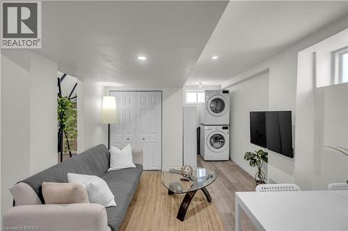 Living area with light wood-finish flooring, recessed lighting, and a stacked washer and dryer unit - 450 Highland Road E, Kitchener, ON - Indoor