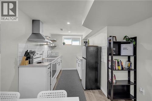 Contemporary kitchen featuring white cabinetry, subway tile backsplash, a stainless steel range hood, and a built-in electric range - 450 Highland Road E, Kitchener, ON - Indoor Photo Showing Other Room
