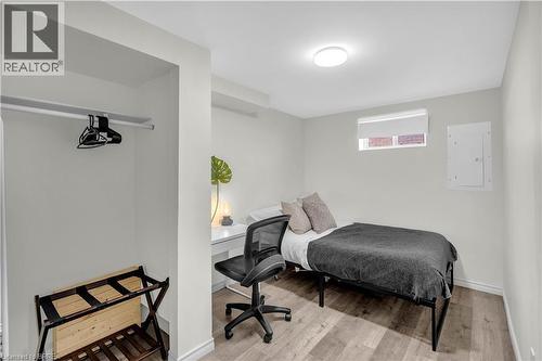 Neutral-toned Bedrppm featuring wood-finish flooring, a built-in closet with hanging rod, a window with a white roller blind, and a flush-mount ceiling light fixture - 450 Highland Road E, Kitchener, ON - Indoor