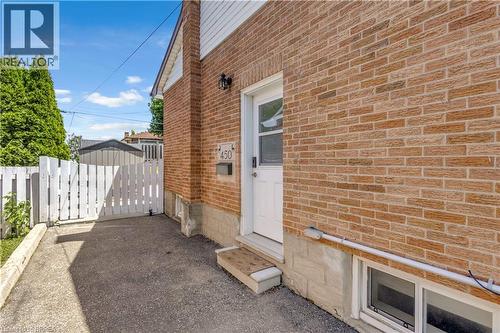 Seperate Entrance Brick exterior featuring a white entry door, exterior wall lantern, and a white picket fence - 450 Highland Road E, Kitchener, ON - Outdoor With Exterior