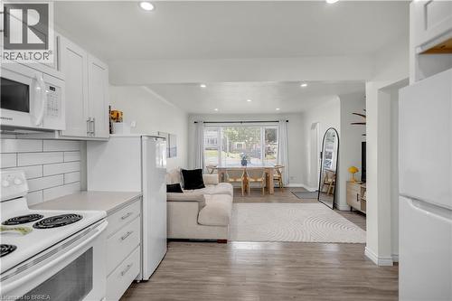 Open-concept living space featuring wood-finish flooring, white cabinetry, integrated microwave, and recessed lighting - 450 Highland Road E, Kitchener, ON - Indoor Photo Showing Kitchen