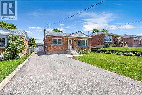 Brick exterior ranch-style home featuring a paved driveway, front steps with white railings, and a manicured front lawn - 450 Highland Road E, Kitchener, ON - Outdoor With Facade