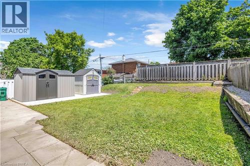 Private backyard featuring two storage sheds, a concrete patio, and a wood privacy fence - 450 Highland Road E, Kitchener, ON - Outdoor