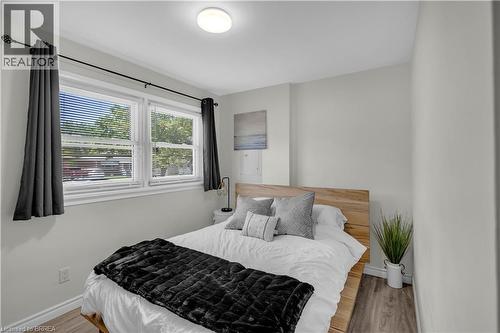 Bright room featuring two windows with white blinds, light gray walls, and wood-finish flooring - 450 Highland Road E, Kitchener, ON - Indoor Photo Showing Bedroom