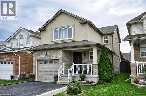 Welcoming two-story residence featuring a cream and brick exterior, attached two-car garage, and a covered front porch with white railings - 156 Copper Leaf Street, Kitchener, ON - Outdoor