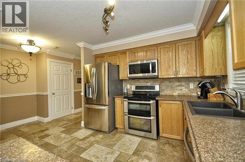 Stainless steel appliances, wood cabinetry, granite-finish countertops, tile flooring, and a mosaic tile backsplash - 156 Copper Leaf Street, Kitchener, ON - Indoor Photo Showing Kitchen With Stainless Steel Kitchen With Double Sink