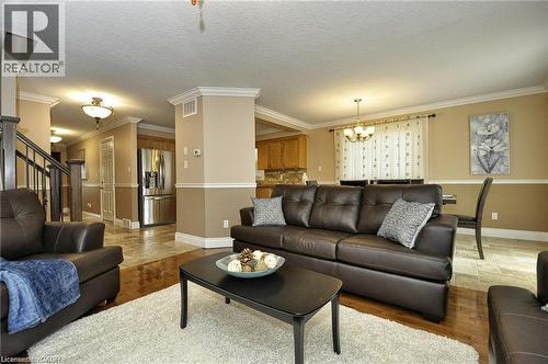 Hardwood flooring, tile flooring, two-tone wall paint, crown molding, and a built-in stainless steel refrigerator - 156 Copper Leaf Street, Kitchener, ON - Indoor Photo Showing Living Room