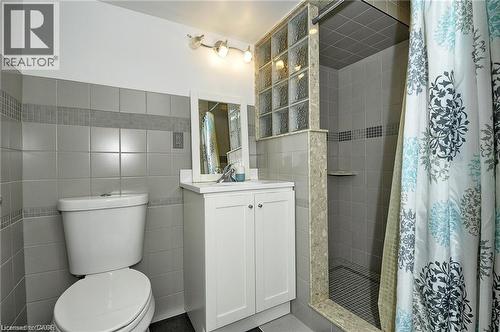 Tiled walls featuring a mosaic accent band, white vanity with an integrated sink, and an enclosed shower with glass block details - 156 Copper Leaf Street, Kitchener, ON - Indoor Photo Showing Bathroom