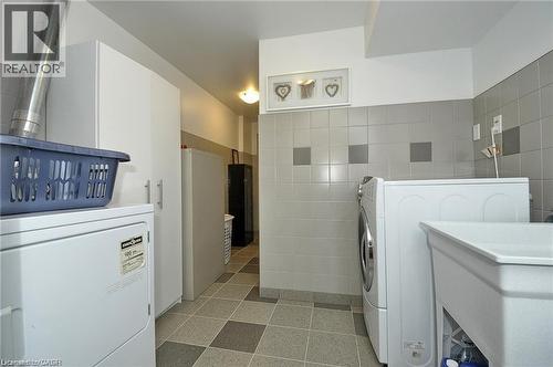 Utility room featuring ceramic tile flooring, tiled walls, and built-in cabinetry - 156 Copper Leaf Street, Kitchener, ON - Indoor Photo Showing Laundry Room