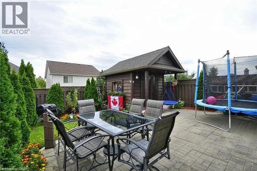 Backyard featuring a paved patio area, mature privacy hedges, a wooden storage shed, and a privacy fence - 156 Copper Leaf Street, Kitchener, ON - Outdoor With Deck Patio Veranda