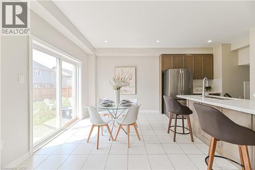 Open-concept kitchen and dining area featuring white tile flooring, stainless steel appliances, and a kitchen island with a light-colored countertop - 24 Weatherall Avenue, Cambridge, ON - Indoor
