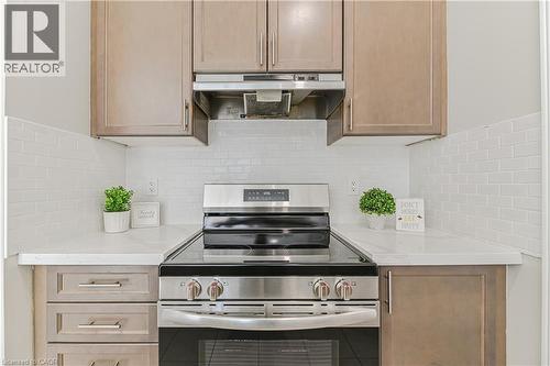 Stainless steel electric range with hood vent, light wood-finish cabinetry, white subway tile backsplash, and light-toned countertops - 24 Weatherall Avenue, Cambridge, ON - Indoor Photo Showing Kitchen