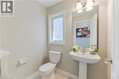 White pedestal sink with chrome faucet, large wall mirror, and modern vanity lighting - 24 Weatherall Avenue, Cambridge, ON - Indoor Photo Showing Bathroom