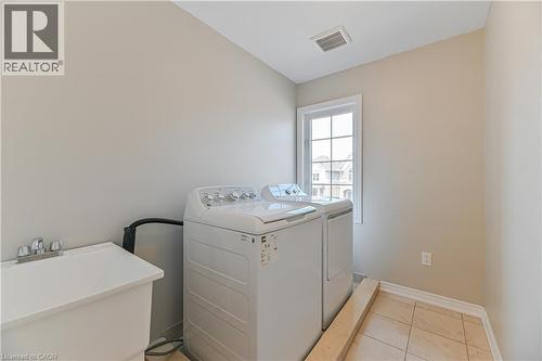 Utility sink, tiled flooring, window with grid panes, and neutral wall paint - 24 Weatherall Avenue, Cambridge, ON - Indoor Photo Showing Laundry Room