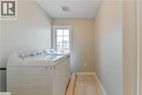 Tiled flooring, light-toned wall paint, a framed window, and white trim details - 24 Weatherall Avenue, Cambridge, ON - Indoor Photo Showing Laundry Room