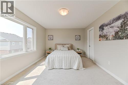 Neutral-toned carpeting and walls, large window with white trim, and a white interior door - 24 Weatherall Avenue, Cambridge, ON - Indoor Photo Showing Bedroom