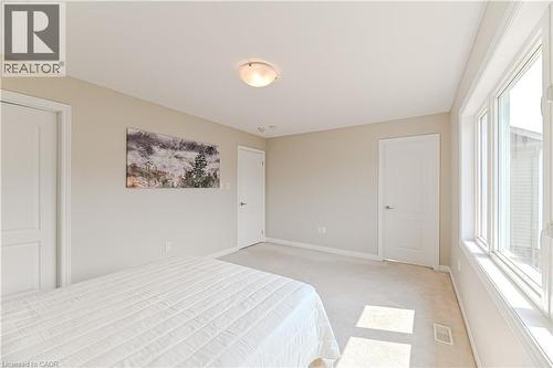 Neutral tone wall paint, carpet flooring, flush mount ceiling light fixture, multiple panel doors, and large multi-pane windows - 24 Weatherall Avenue, Cambridge, ON - Indoor Photo Showing Bedroom