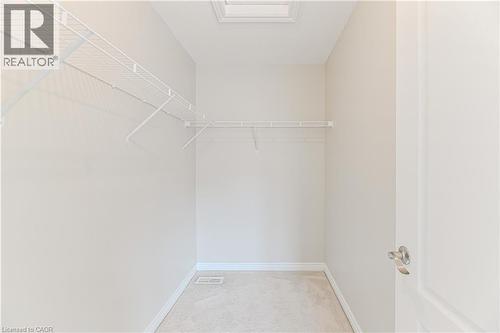 Recessed ceiling light with white trim, white wire shelving, light-toned carpeting, white baseboards, and a white interior door with brushed nickel hardware - 24 Weatherall Avenue, Cambridge, ON - Indoor With Storage