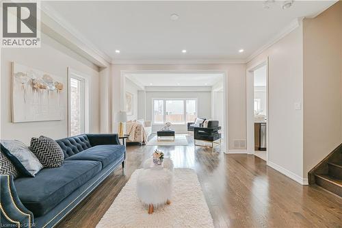Wide plank wood-finish flooring throughout, featuring a bright, open living space with recessed lighting and crown molding - 24 Weatherall Avenue, Cambridge, ON - Indoor Photo Showing Living Room