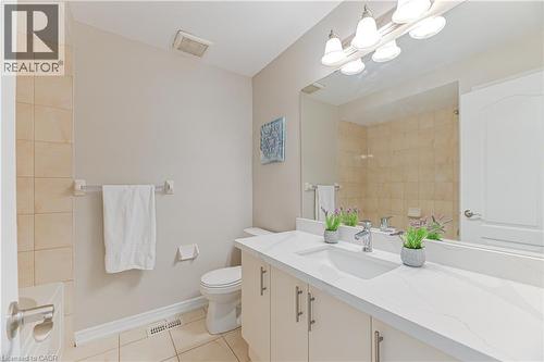 Bathroom featuring a single vanity with stone-finish countertop, undermount sink, and light-toned cabinetry - 24 Weatherall Avenue, Cambridge, ON - Indoor Photo Showing Bathroom